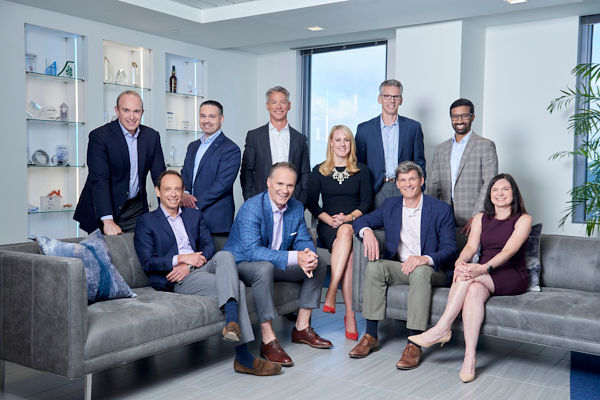 team gathered around couch smiling for professional photo