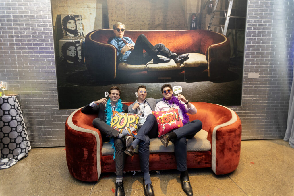 3 men sitting on a couch holding signs