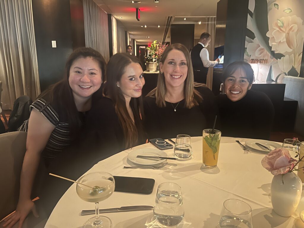 a group of women sitting a table smiling to take a picture