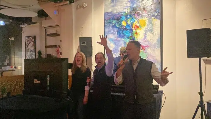 two men and a woman singing karaoke on stage