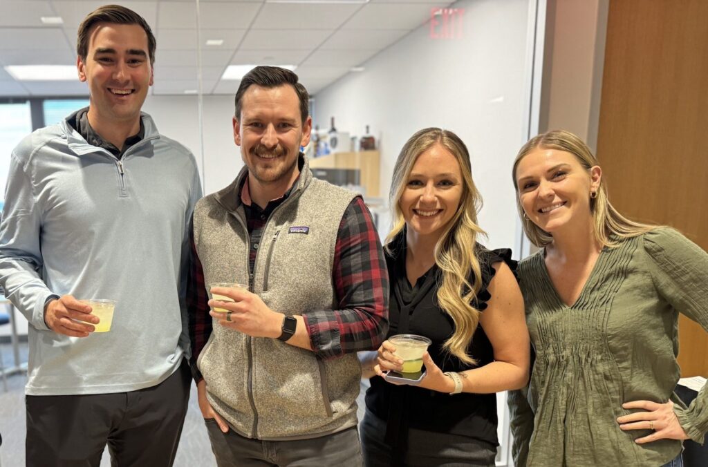 men and woman smiling holding drinks - team happy hour